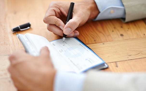 Photo of a person's hands as they are writing a check